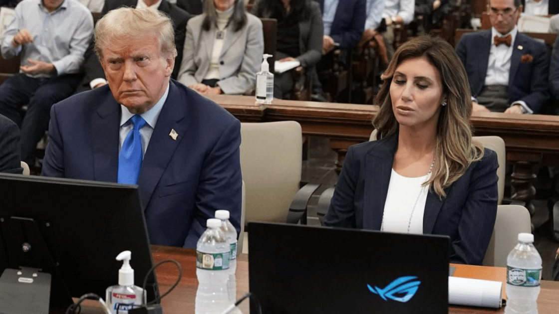 A photo of Donald Trump sitting next to his lawyer, who has an Asus gaming laptop. Its glowing RGB logo is clearly visible.